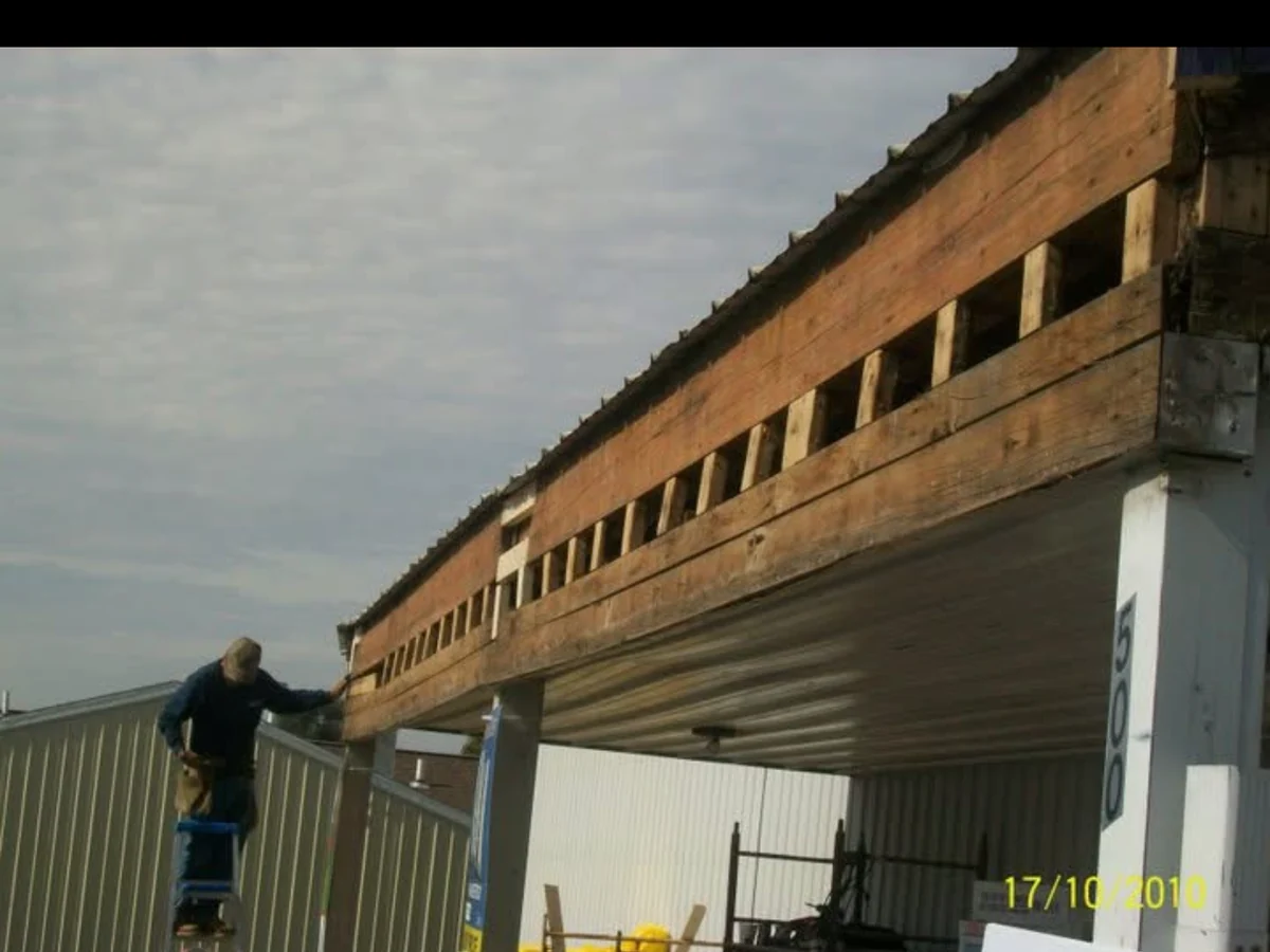 In progress: purple wood fascia removed from the storefront, exposing the framing line beneath the roof