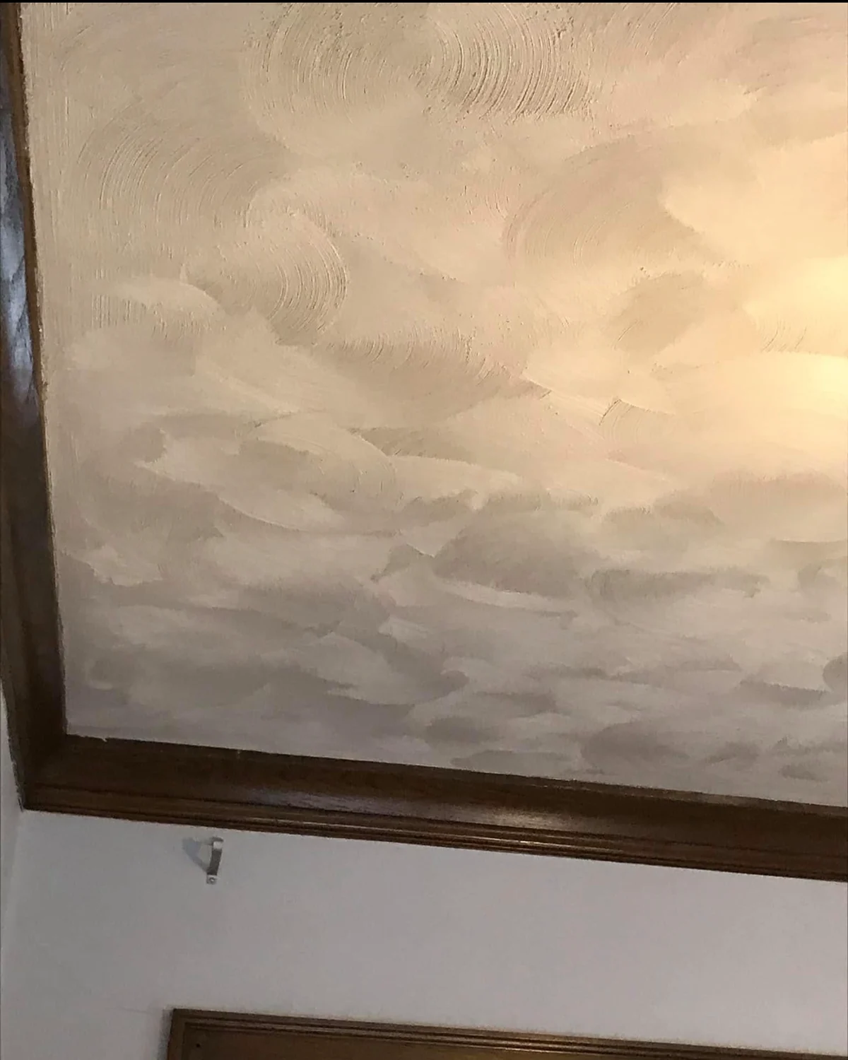 Close view of a hand-varied calico plaster ceiling with light moving across the textured finish
