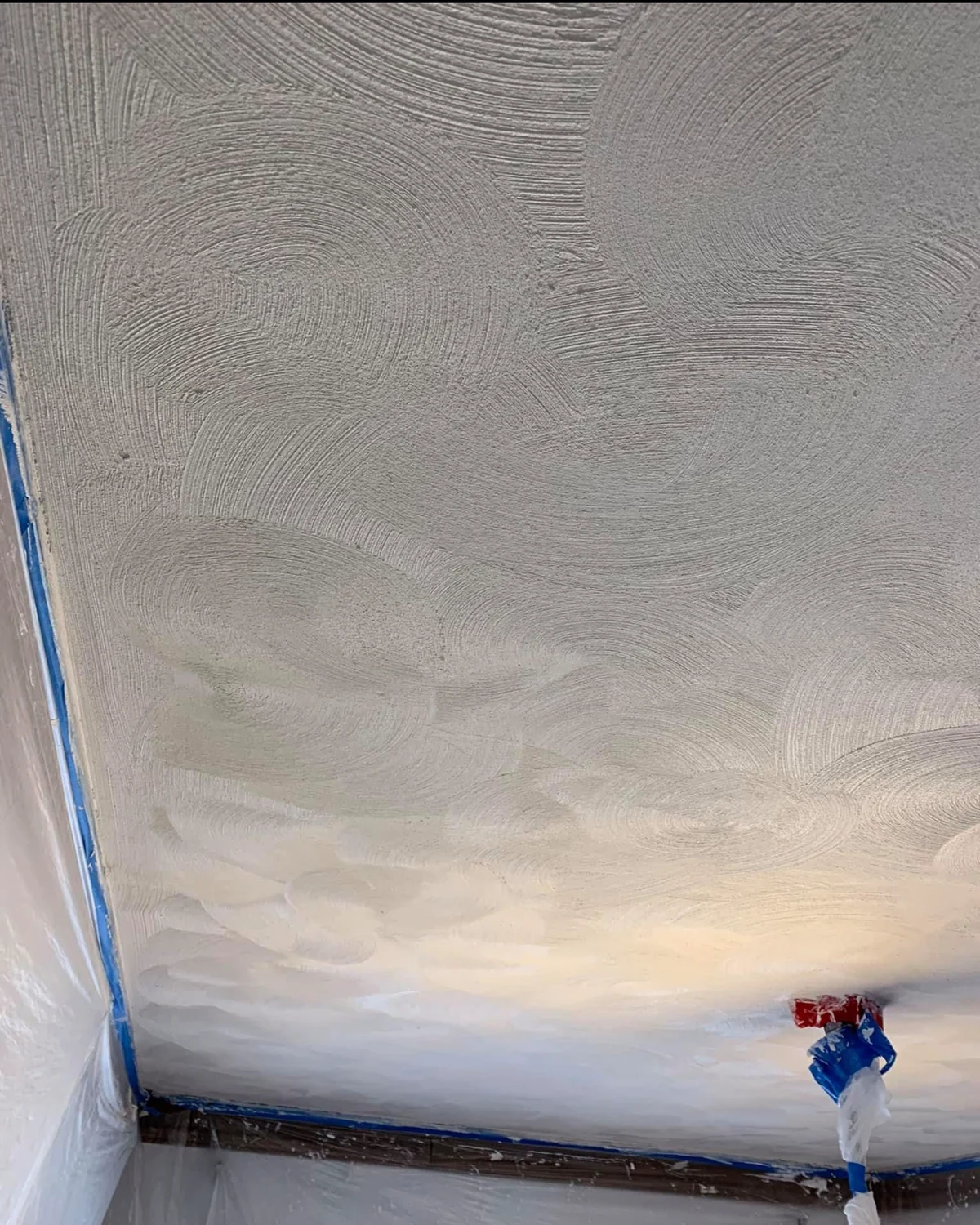 In progress: a textured plaster ceiling being hand-worked near taped trim before the room is finished