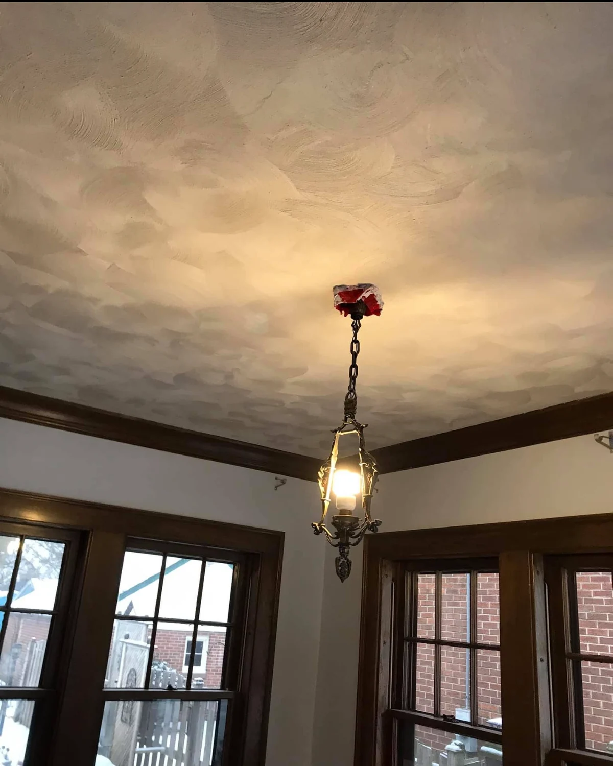 Finished calico plaster ceiling in a room with dark wood trim, French swirl texture catching the warm natural light