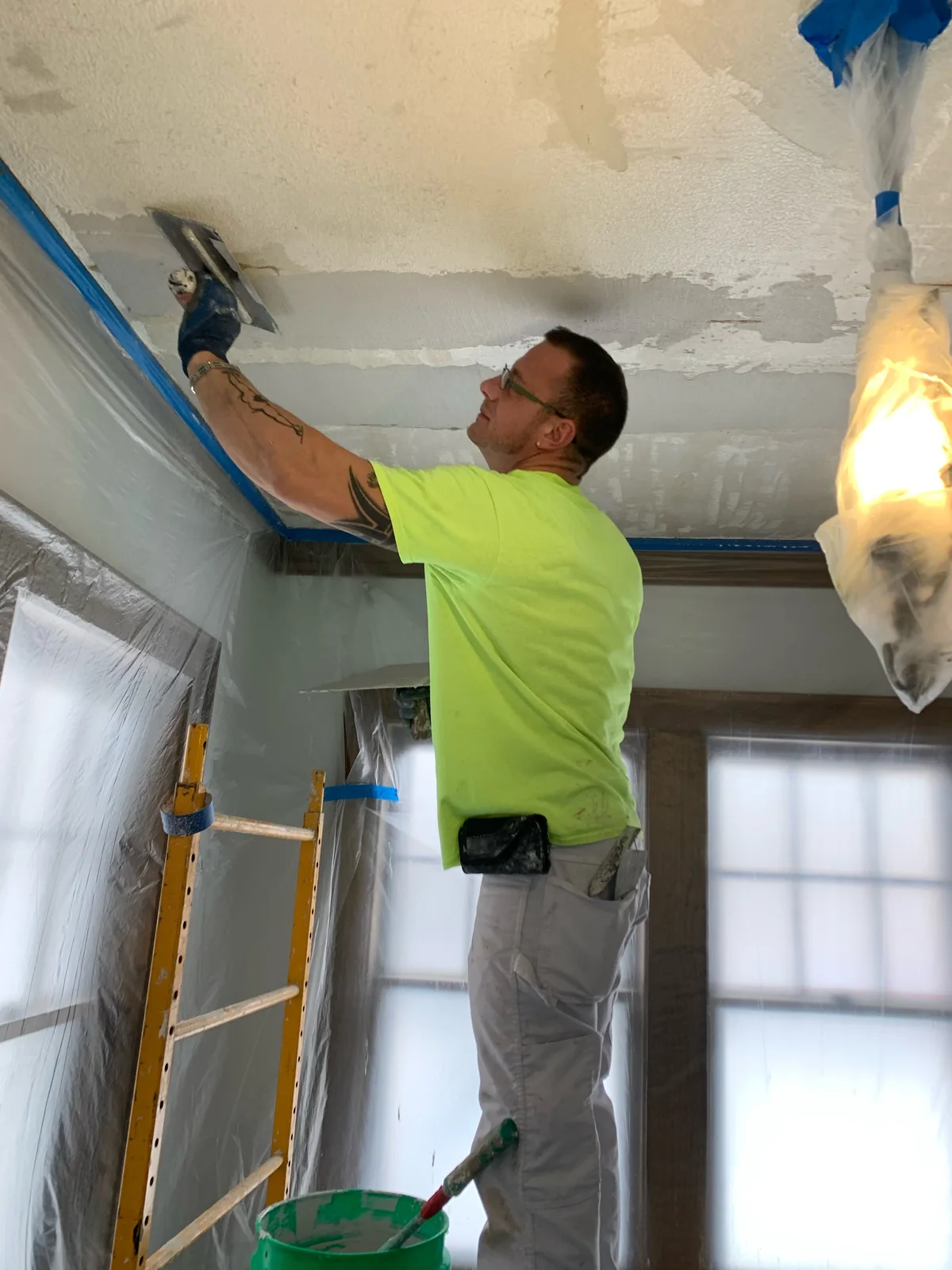 Overhead finish coat: Tightening a fresh coat across a repaired ceiling.