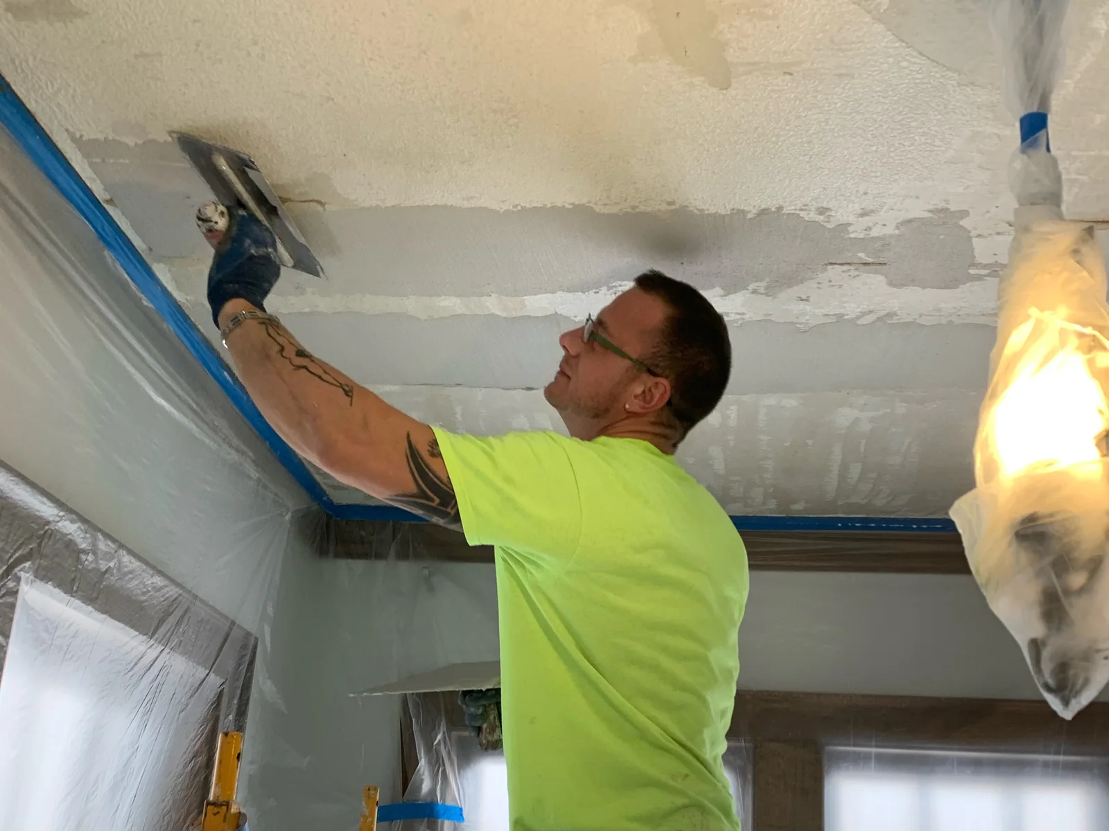 Troweling a new finish coat onto a repaired plaster ceiling