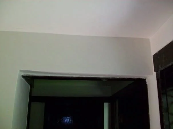 After: the wall above the doorway finished smooth in lime and painted, with no sign of the damage