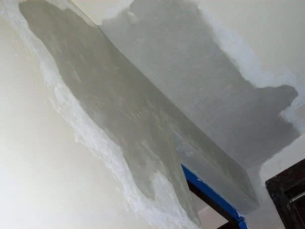 During: base-coat plaster built up across the wall and ceiling corner beside the door