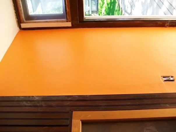 The coach-house foyer wall painted bright orange beneath dark-stained wood trim and windows