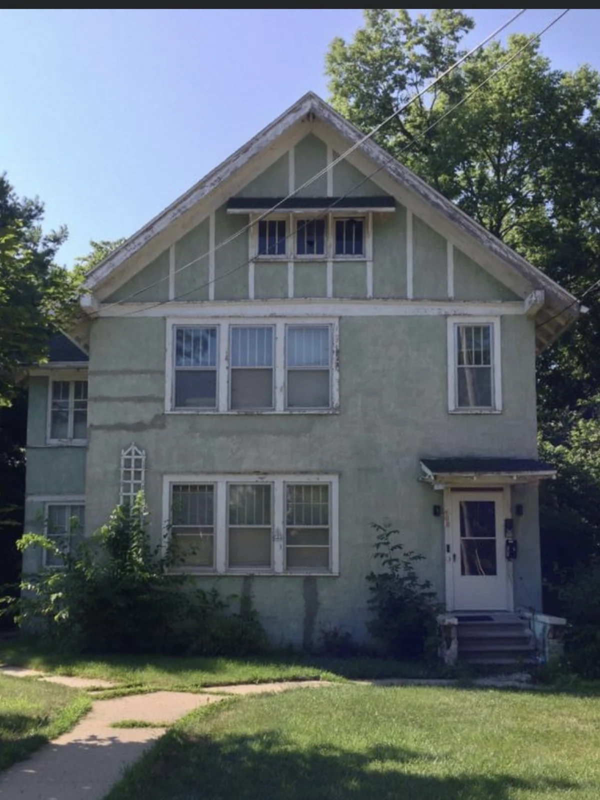 After: the same two-story Dixon residence with a clean light exterior finish, bright white trim and a coordinated front entry