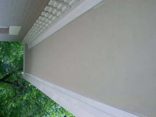 After: the same soffit run re-stuccoed and painted, smooth and continuous beneath the dentil trim