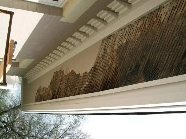 Before: a long section of stucco soffit fallen away beneath the dentil trim, exposing the old wood lath
