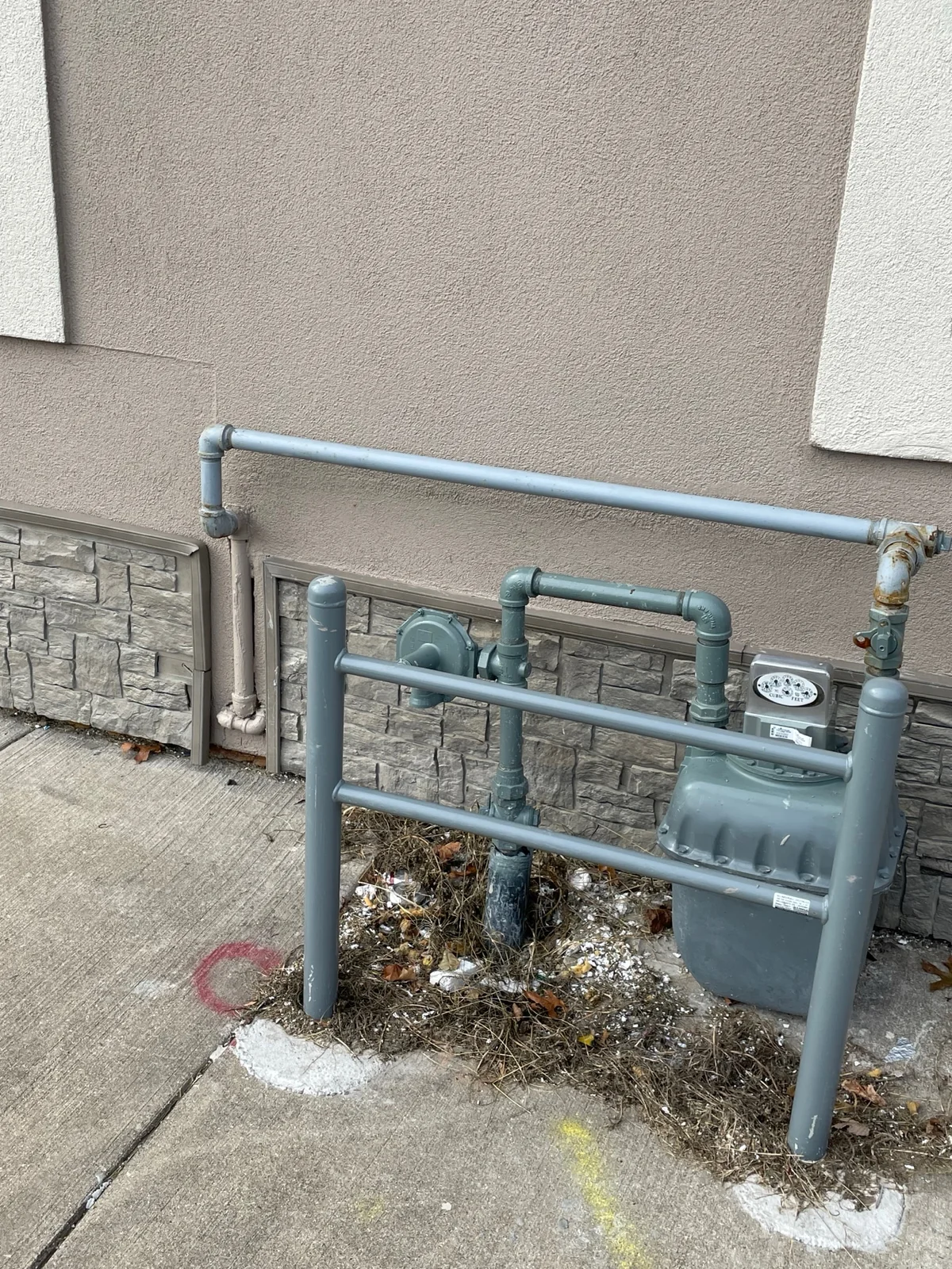 After: the same wall section beside the gas meter repaired, with a smooth continuous finish matching the rest of the building