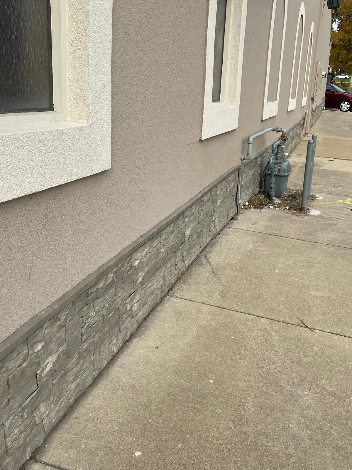 After: looking down the repaired wall, the EIFS finish reads as one continuous surface above the stone-look base