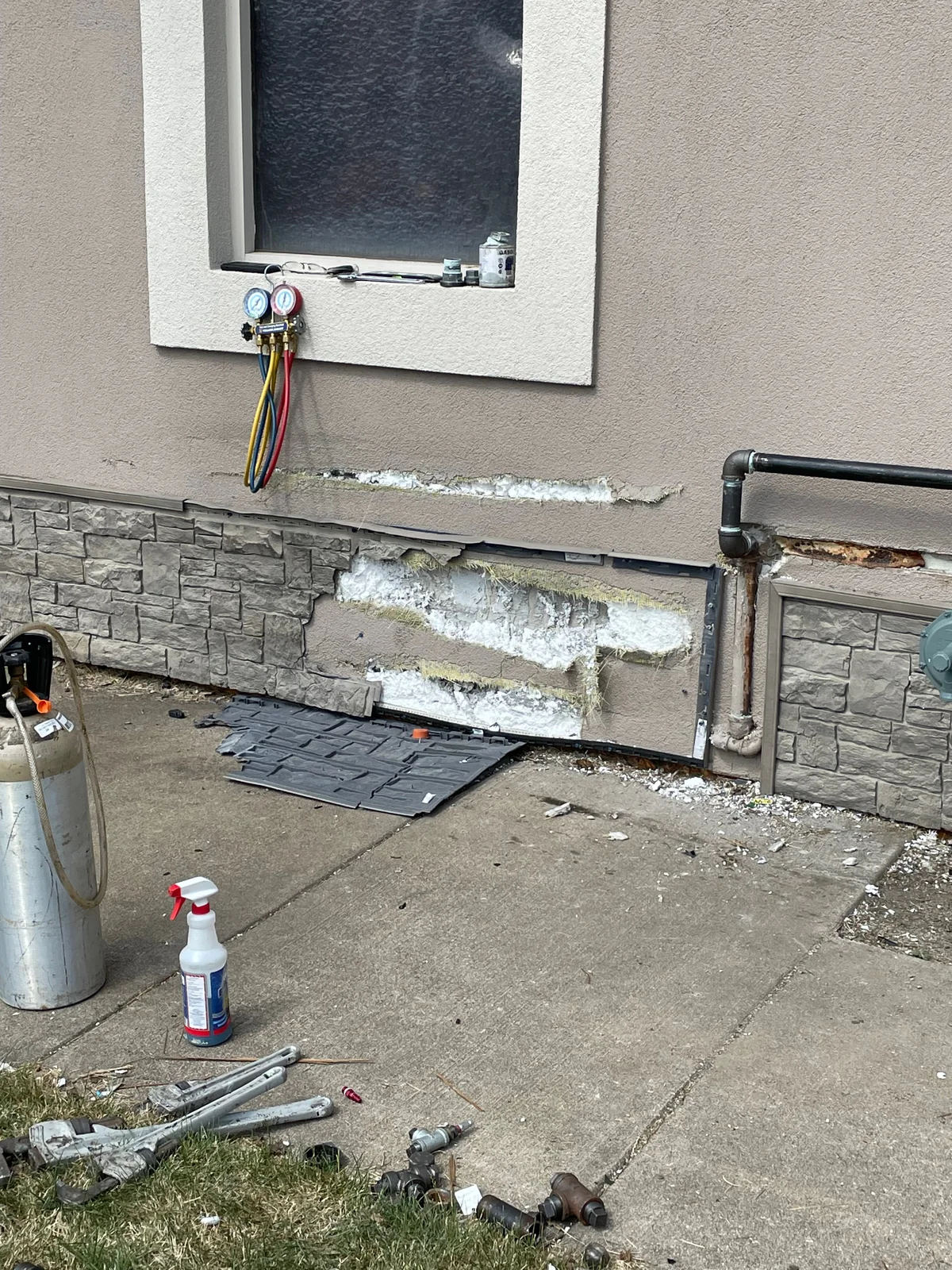 Before, close-up: the finish coat and mesh peeled back to the foam insulation board where the car struck the building