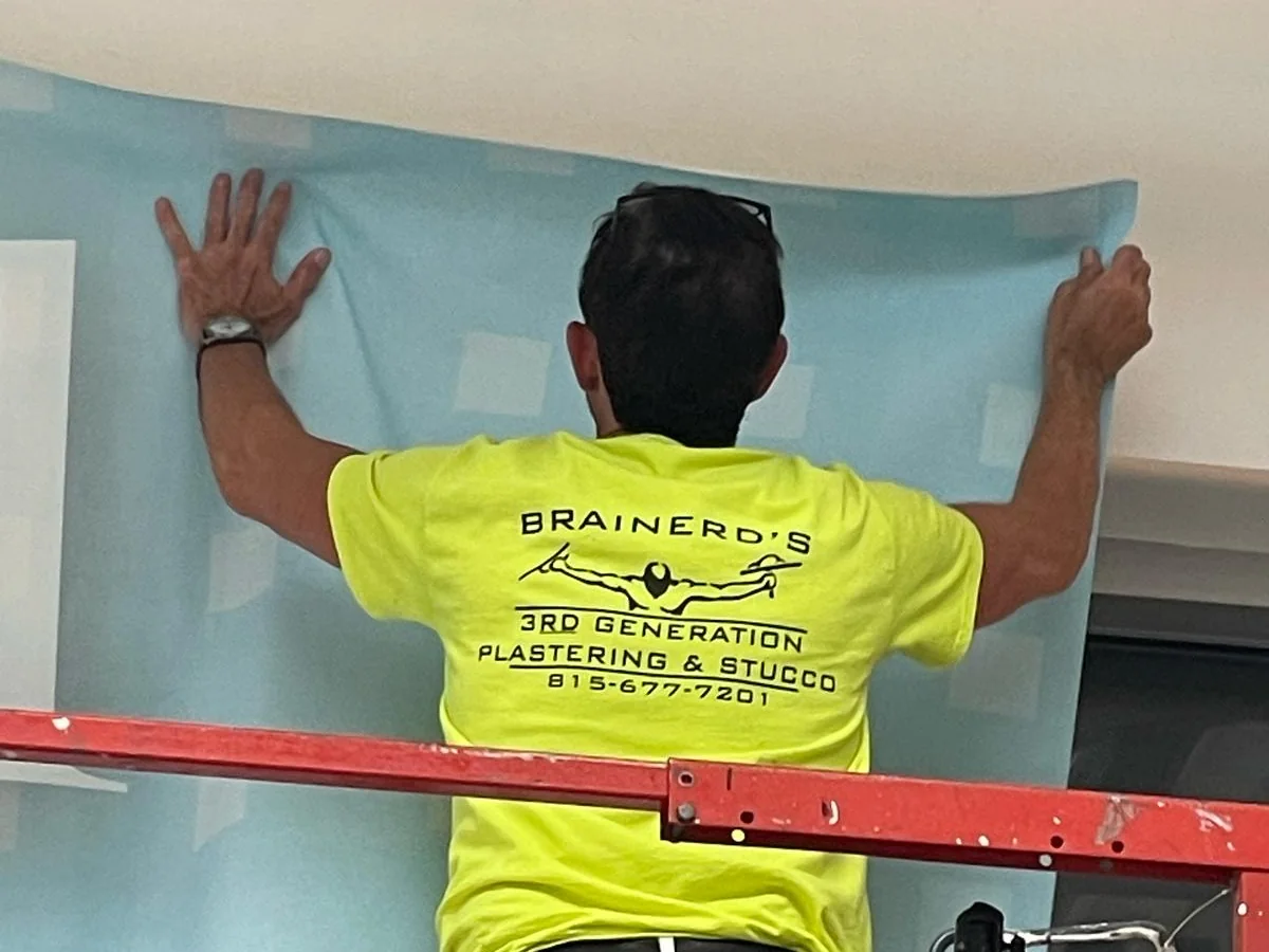 Hanging a commercial wall covering from a lift, in a 3rd Generation shirt